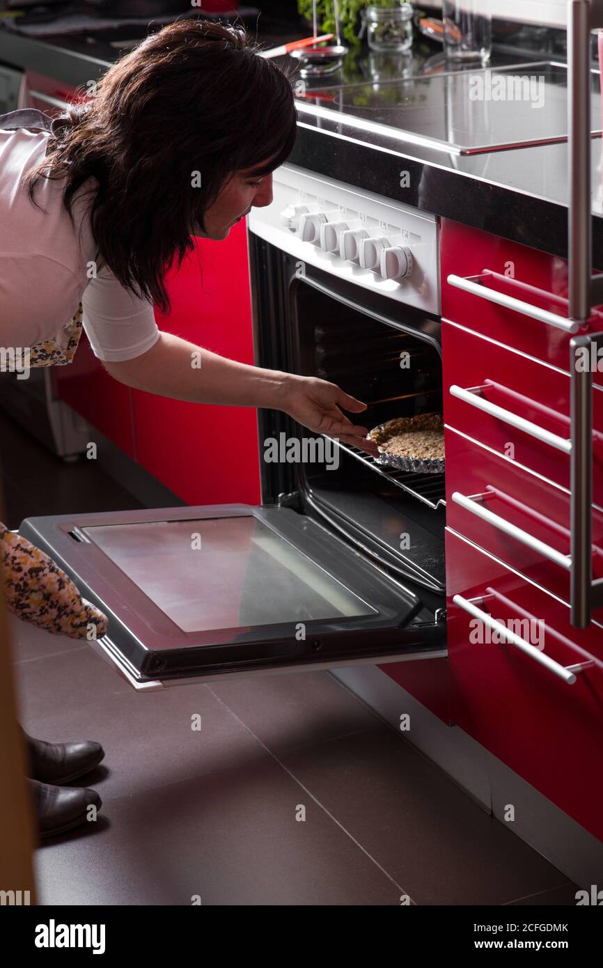 Mujer poniendo un pastel en el horno Fotografía de stock - Alamy