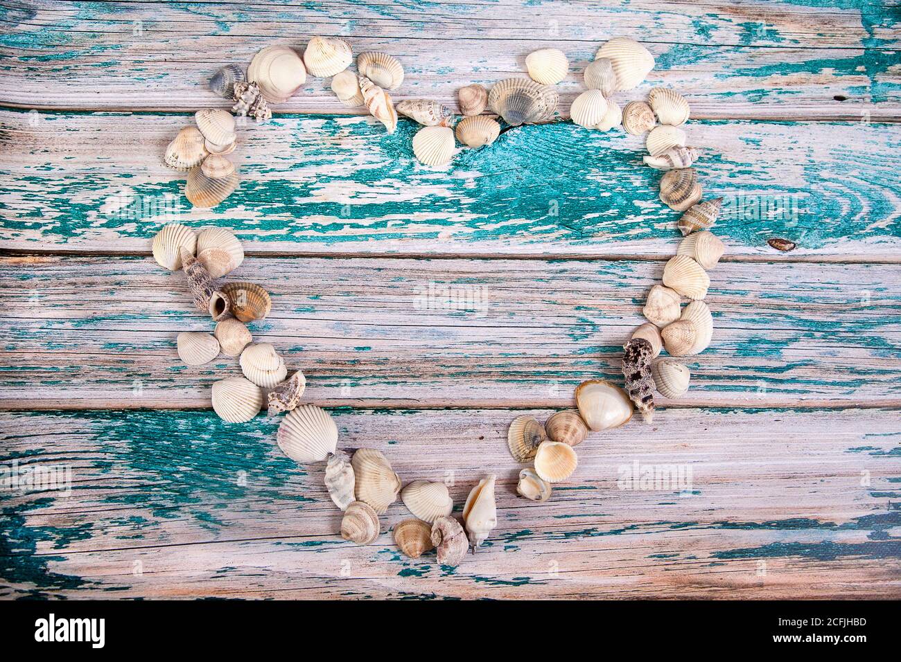 Conchas de mar dispuestas en forma de corazón sobre un fondo de madera azul. Copiar espas Foto de stock