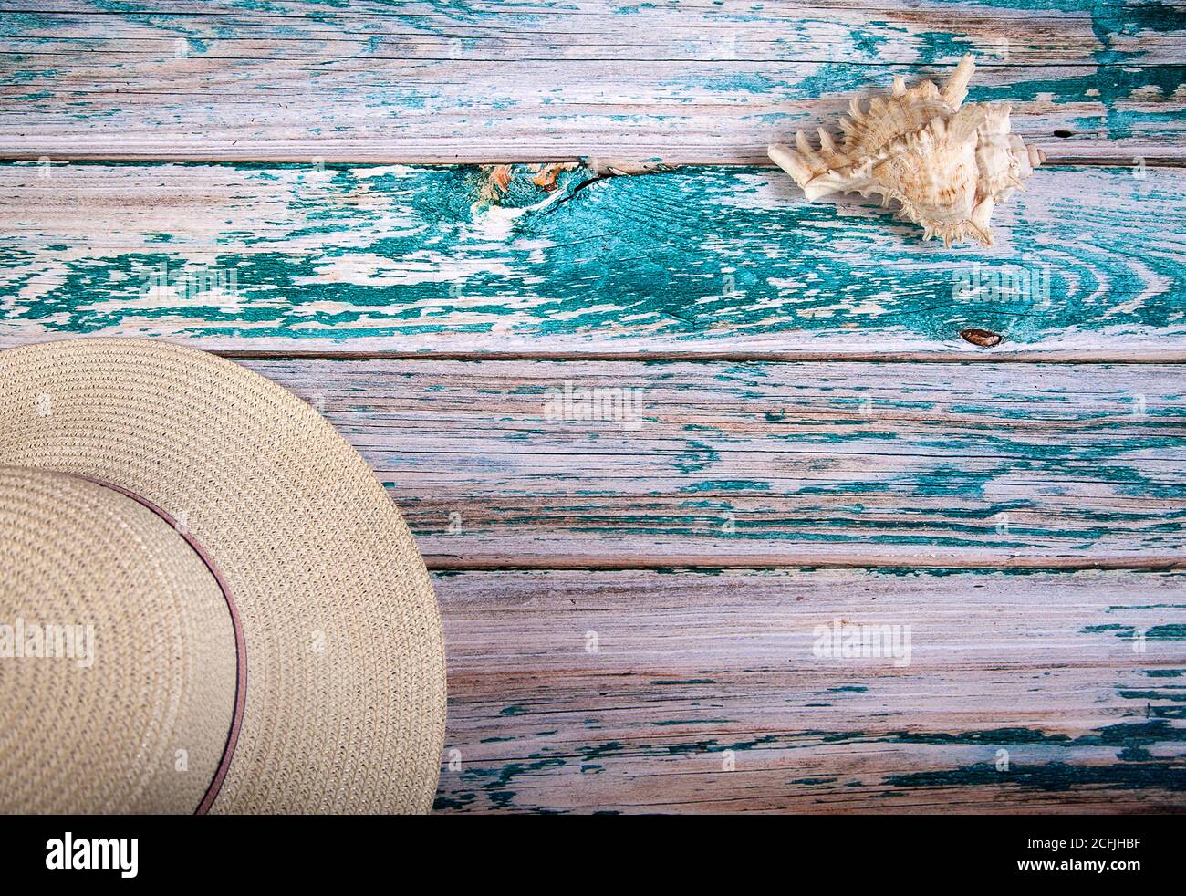 Una concha de mar y un sombrero de paja blanca yacen sobre un fondo de madera azul. Vista desde arriba. Copiar spaes Foto de stock