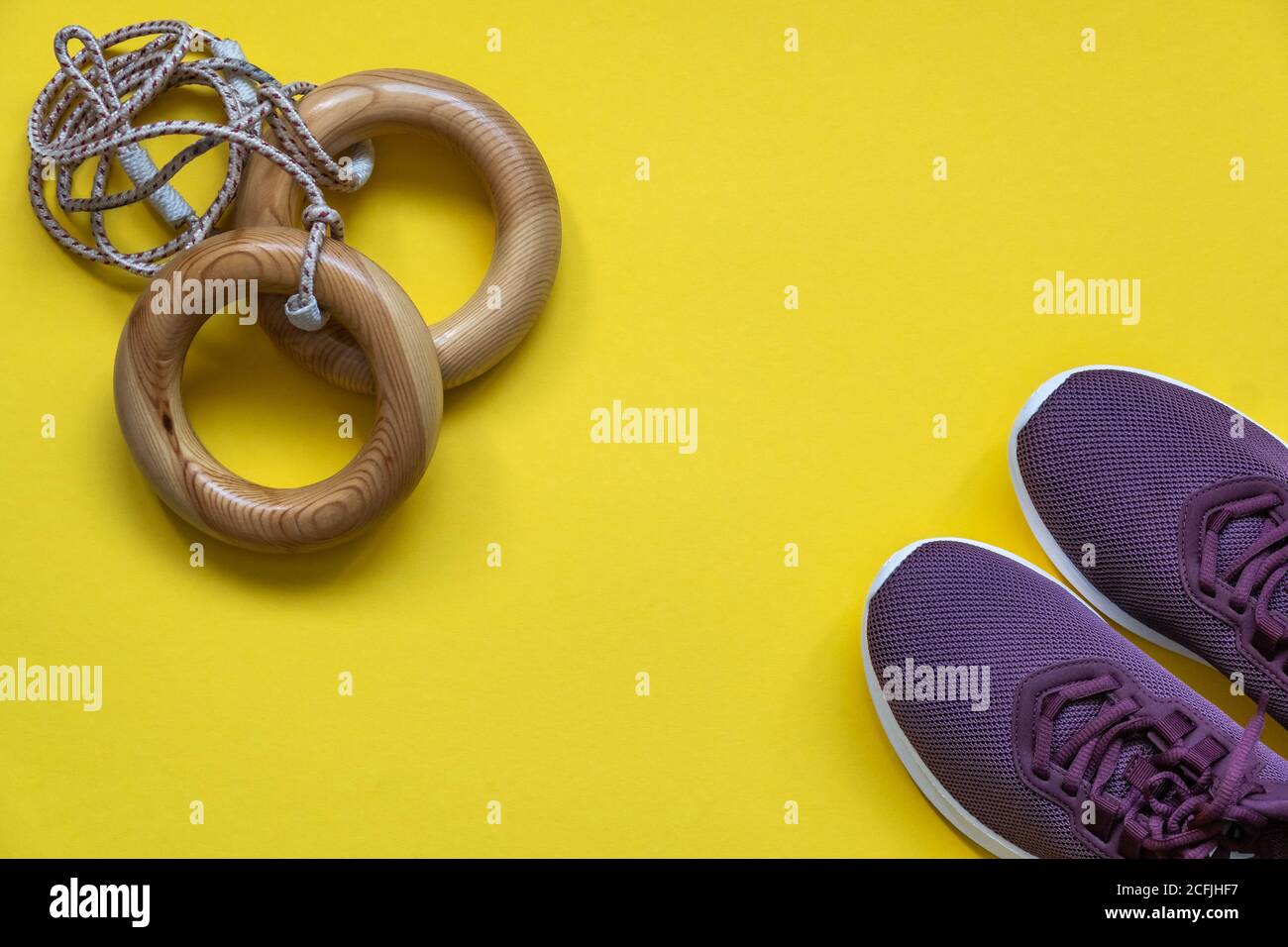 Anillos deportivos y zapatillas de deporte para entrenamientos en casa y en el gimnasio sobre un fondo amarillo. Concepto de cuidado corporal, estilo de vida activo. Vista superior. Espacio para texto. Foto de stock