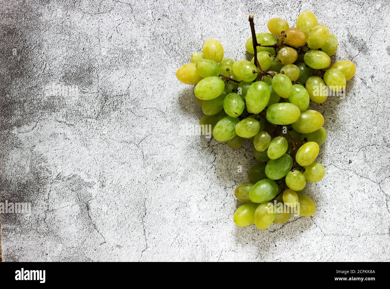 Racimos de uvas de color ámbar sobre un fondo de hormigón gris. Foto de stock