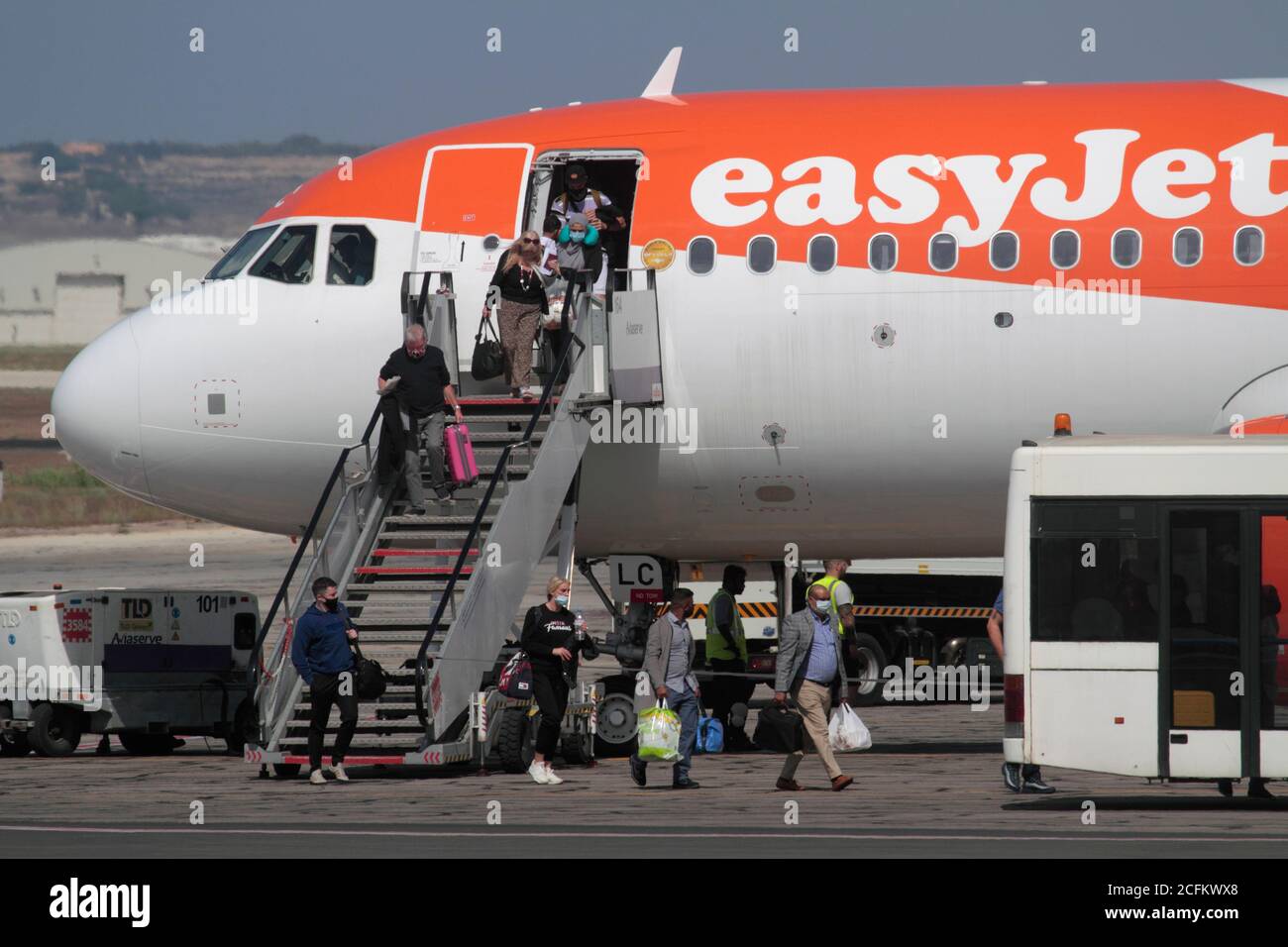Los pasajeros que lleven mascarillas desembarcan de un avión a reacción EasyJet Airbus A320neo en Malta. Impacto del coronavirus COVID-19 en los viajes aéreos. Foto de stock