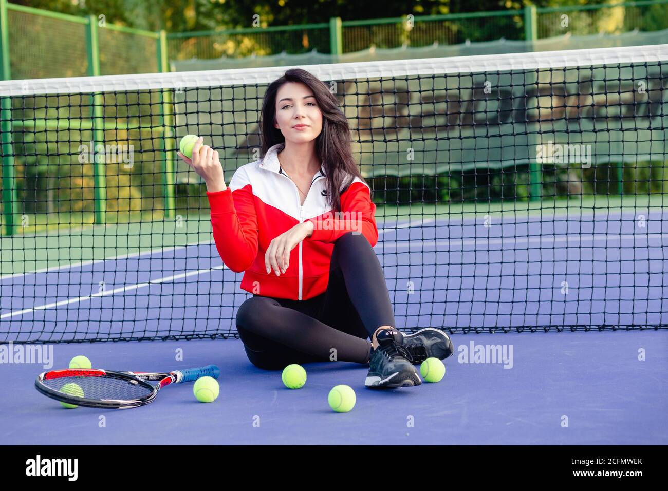 Joven bonita mujer sentada apoyada en la red de tenis, descansando  relajándose después del entrenamiento. Retrato de deportista en pista azul  de tenis. Vida sana Fotografía de stock - Alamy