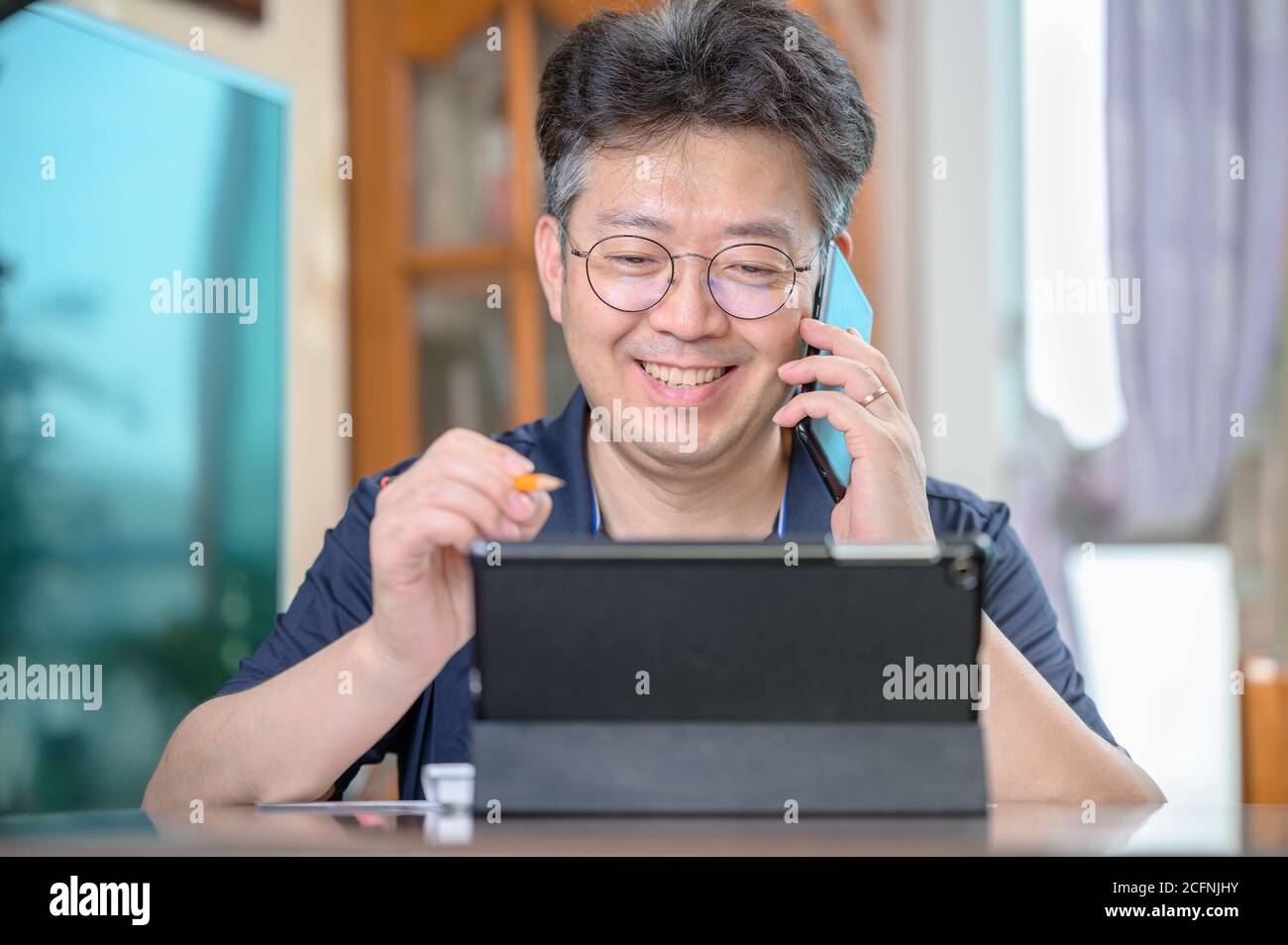 Hombre asiático de mediana edad que trabaja en casa. Concepto de teletrabajo. Foto de stock