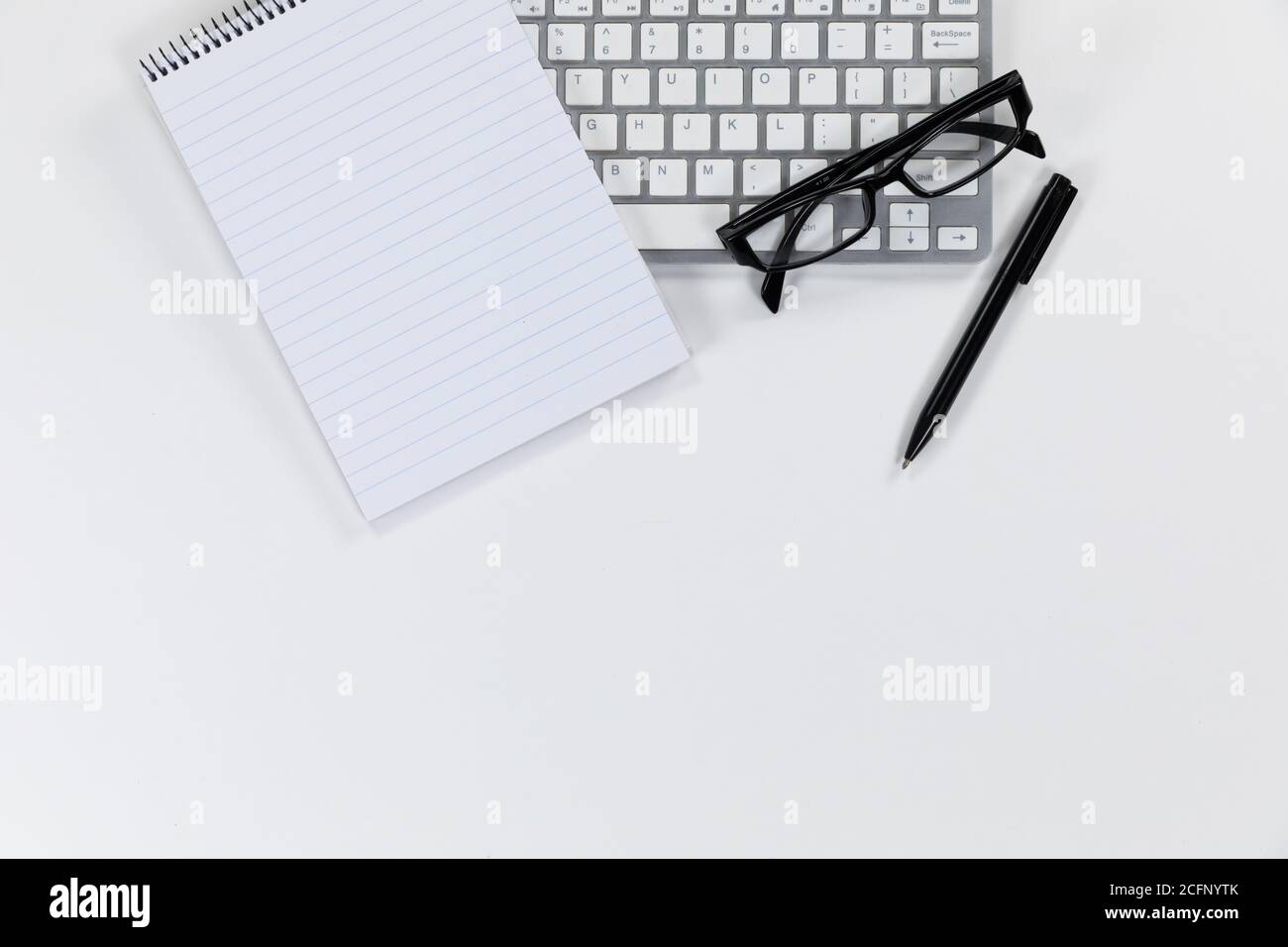 Vista de una palabra clave con un cuaderno y un bolígrafo y gafas sobre fondo blanco Foto de stock