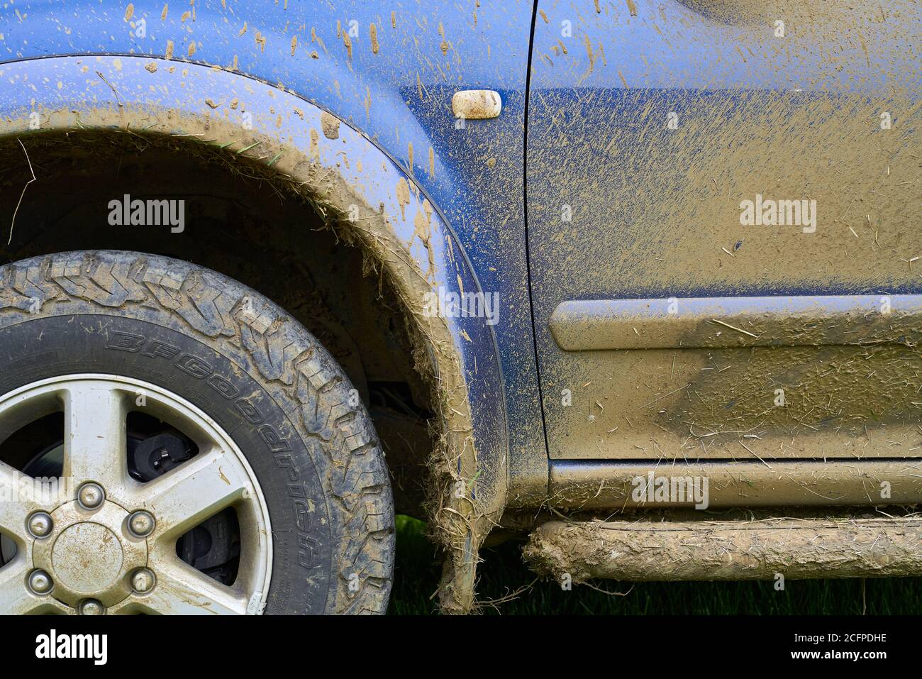 vista lateral parcial de un 4x4 azul y todo el terreno neumático salpicado de barro sucio y muddy en necesidad de un limpio Foto de stock