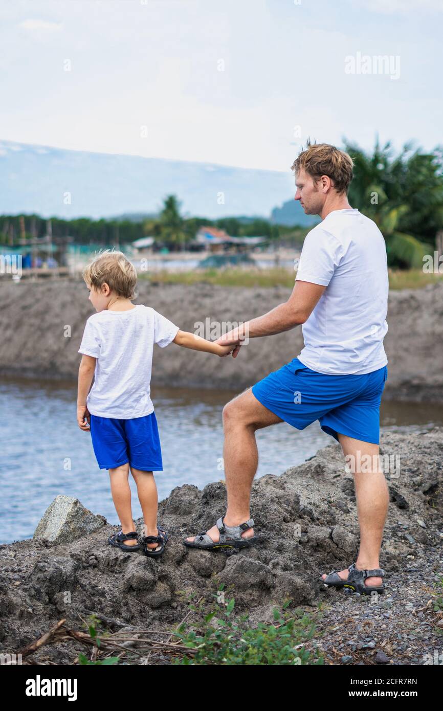 Padre e hijo caminar a lo largo del hombre hecho cría peces lago de fondo  de montaña. Feliz infancia. Hogar educación infantil natural, día de los  padres, papá Fotografía de stock -