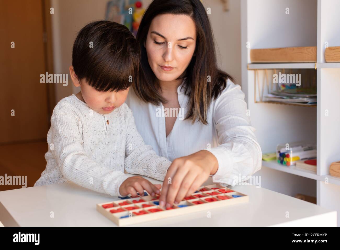 Lillte Kid aprendiendo a escribir y leer con un alfabeto y la ayuda de la madre o del maestro. Resolución de problemas en casa. Comunidad de aprendizaje. Escuela Montessori Foto de stock