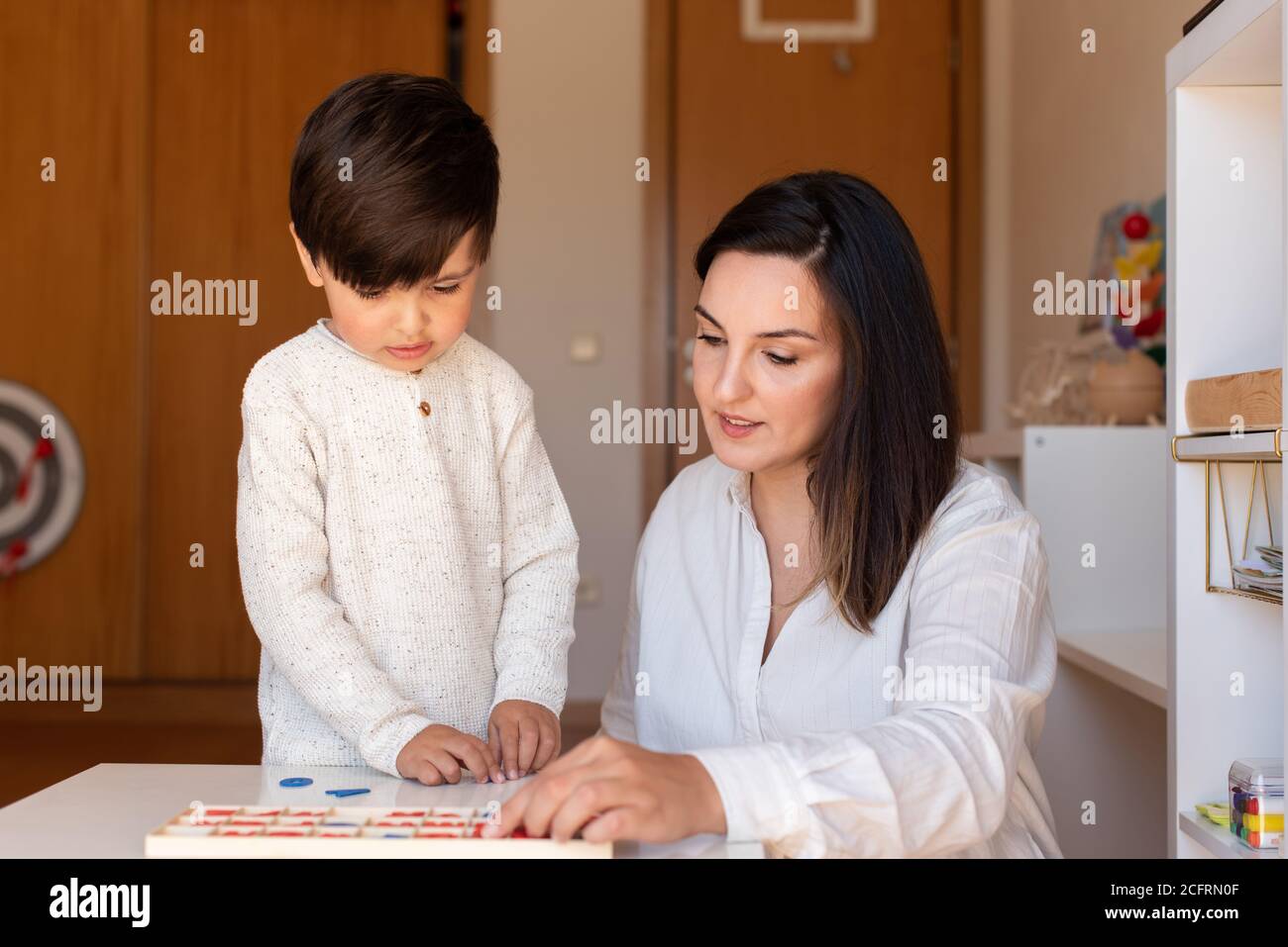 Lillte Kid aprendiendo a escribir y leer con un alfabeto y la ayuda de la madre o del maestro. Resolución de problemas en casa. Comunidad de aprendizaje. Escuela Montessori Foto de stock