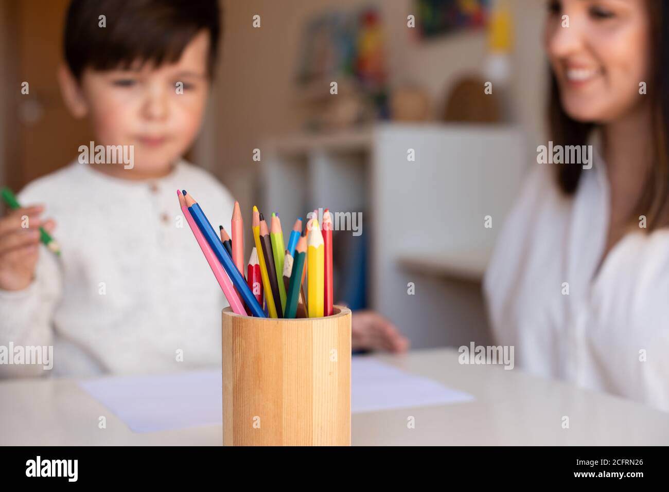 Pequeño niño de preescolar dibujo con lápices de colores con madre o maestro educador. Céntrese en los lápices. Homeschooling. Comunidad de aprendizaje. Montess Foto de stock
