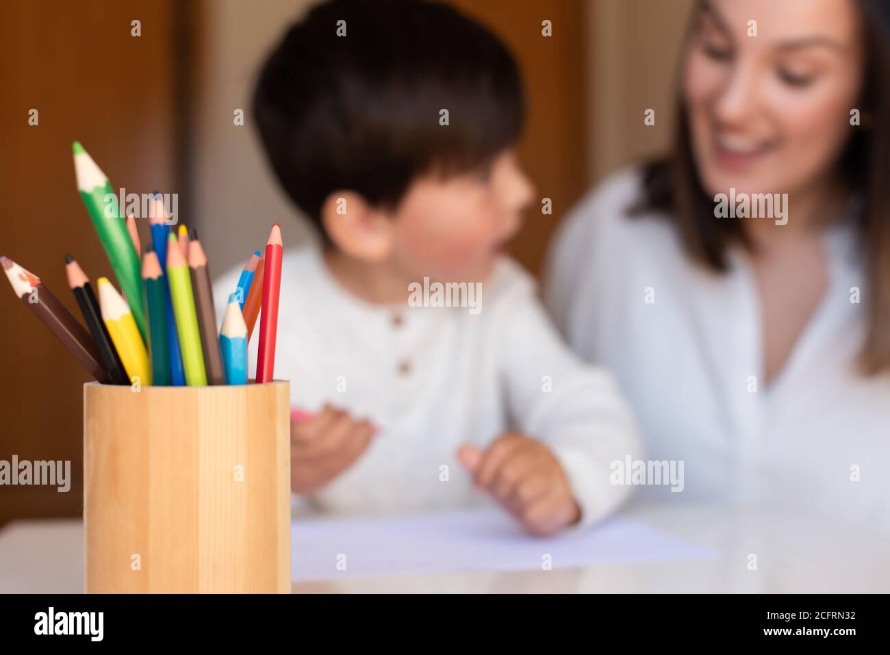 Pequeño niño de preescolar dibujo con lápices de colores con madre o maestro educador. Céntrese en los lápices. Homeschooling. Comunidad de aprendizaje. Montess Foto de stock