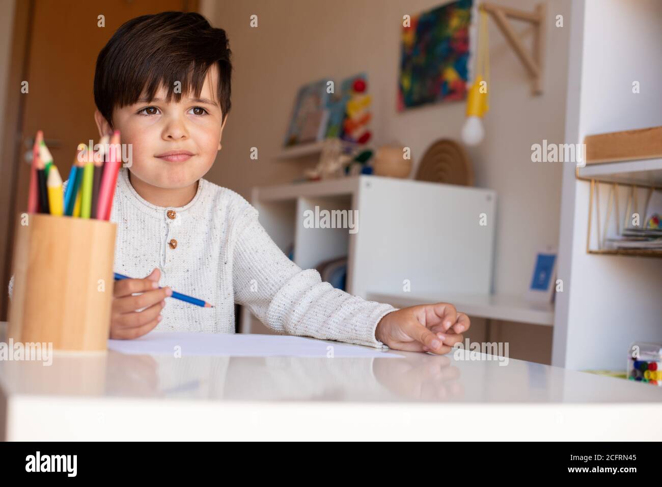 Pequeño niño de preescolar dibujo con lápices de colores. Homeschooling. Comunidad de aprendizaje. Escuela Montessori. Foto de stock