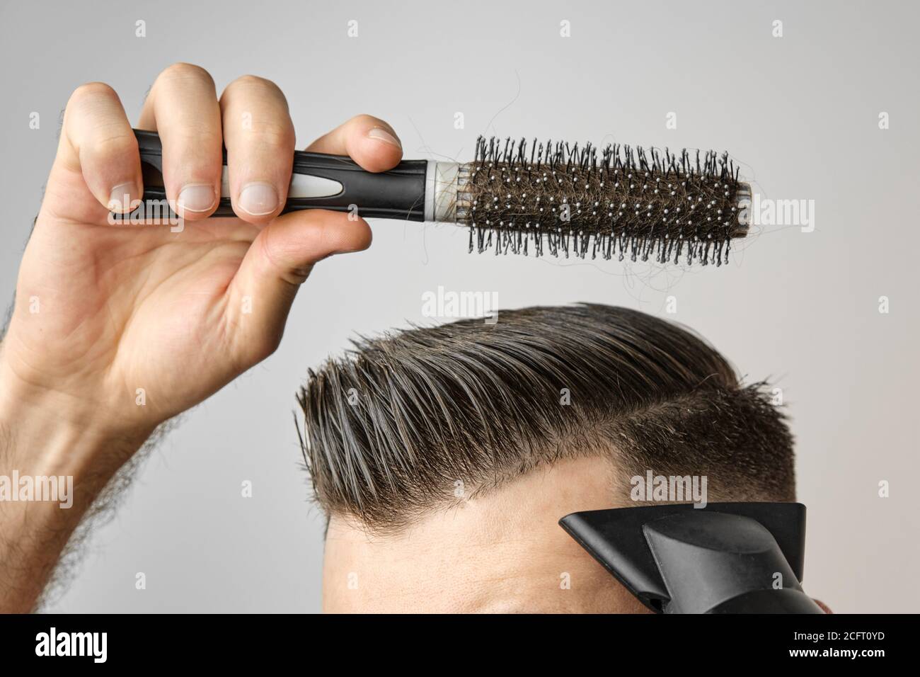 Hombre moldeando su cabello con secador de pelo y cepillo redondo. Cuidado  del cabello en casa después de la peluquería. Man moda y corte de pelo  moderno Fotografía de stock - Alamy