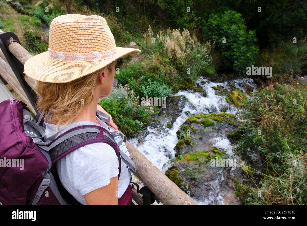 Mujer con un sombrero en un puente y un río. Foto de stock