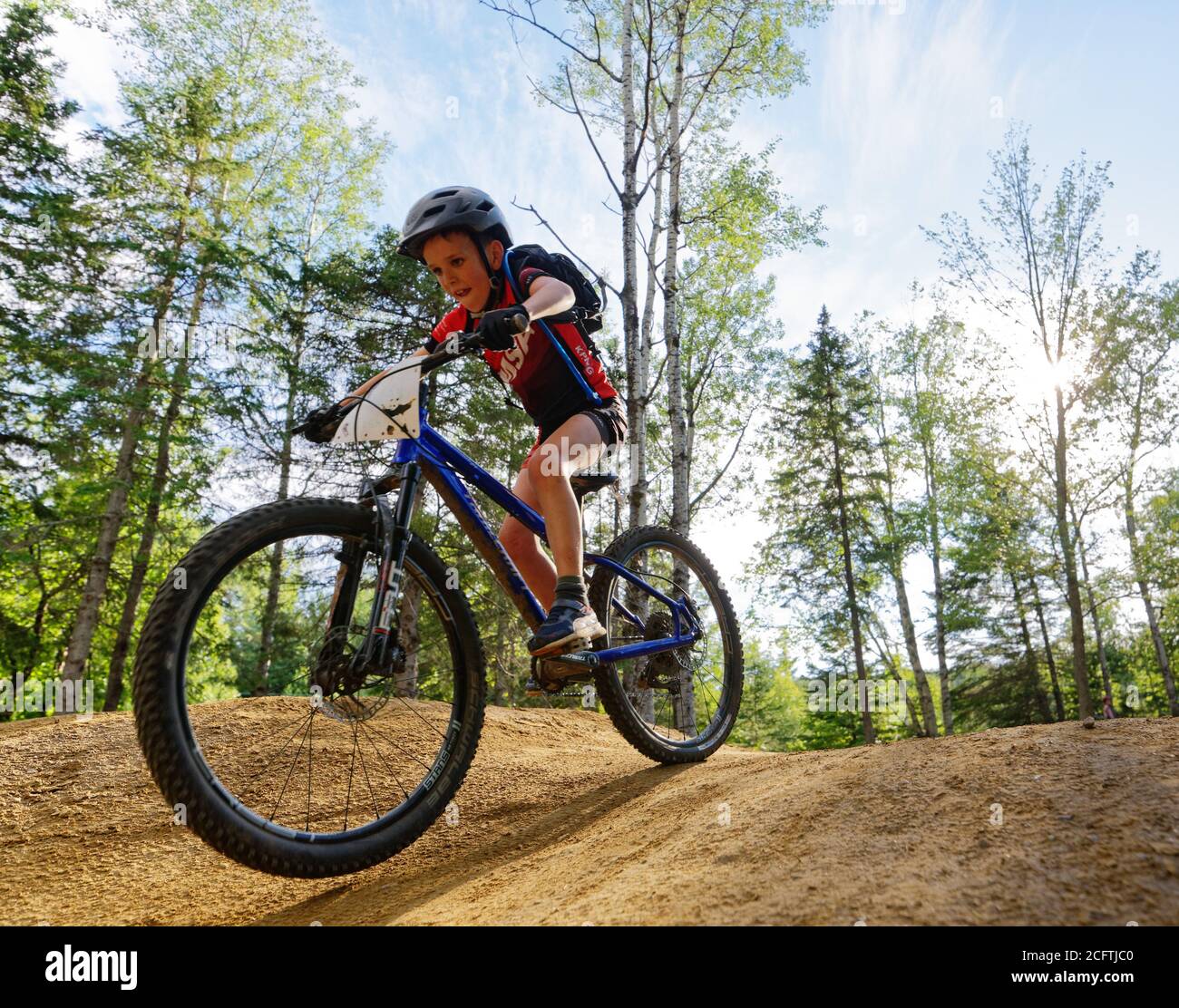 Un niño pequeño (8 años) saltando en su bicicleta de montaña Foto de stock