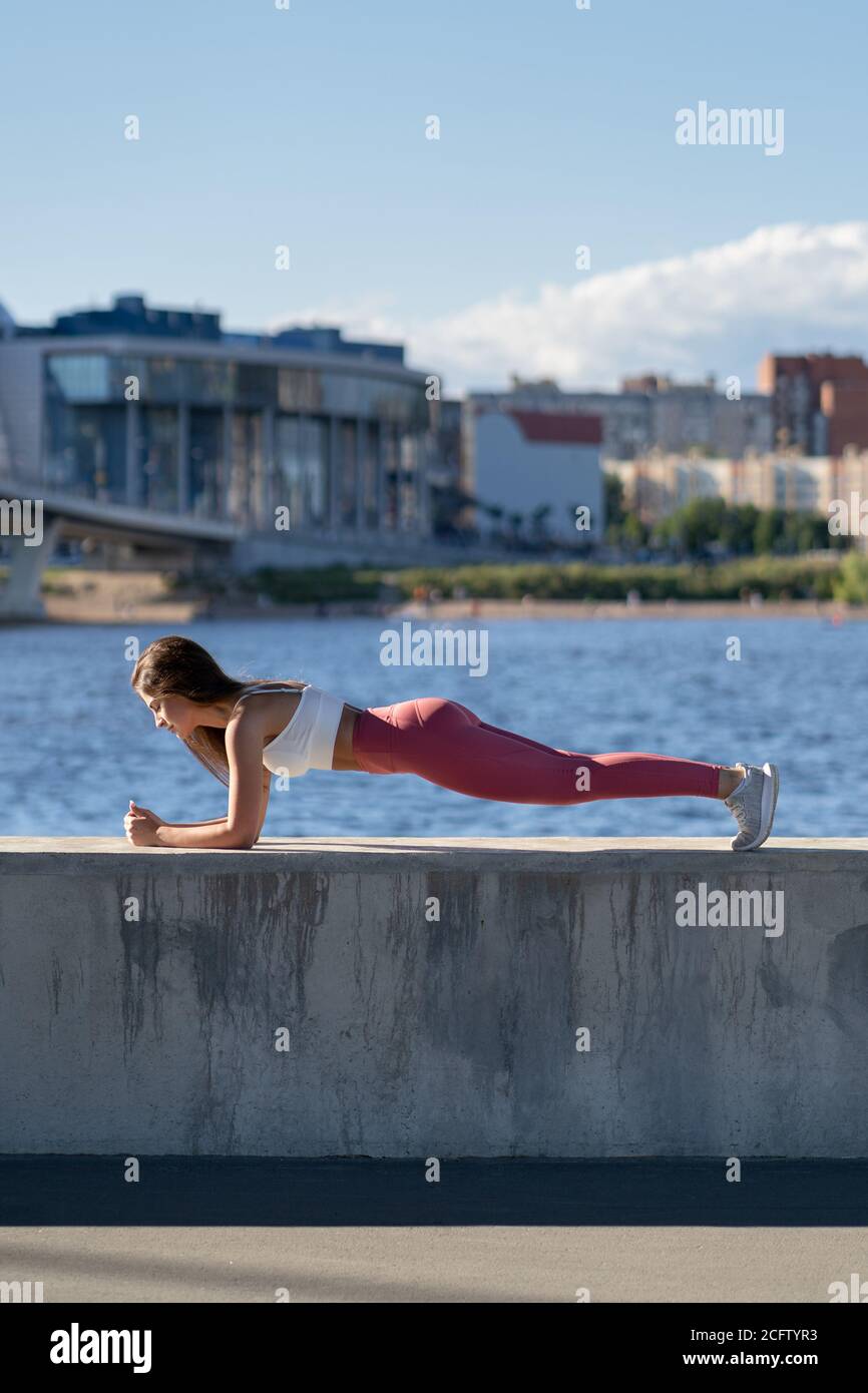 Ajuste a la mujer atlética joven en la pierna rosada haciendo ejercicio