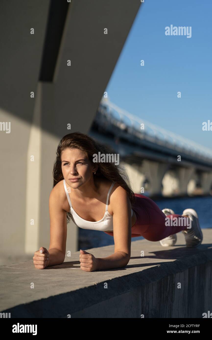 Ajuste a la mujer atlética joven en la pierna rosada haciendo ejercicio
