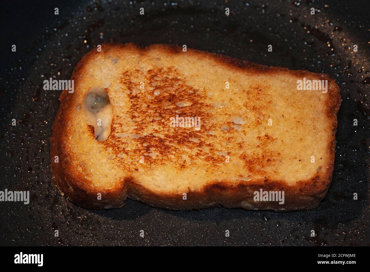 foto de arte de croutons de una rebanada de pan frito en mantequilla sobre una sartén negra Foto de stock