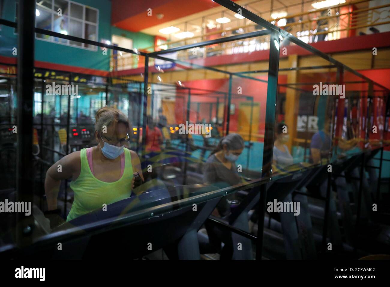 Los miembros hacen ejercicio en máquinas equipadas con paneles de plástico  para asegurar una distancia segura entre los asistentes al gimnasio, en el  Bally Sport Center, después de una cuarentena de cinco