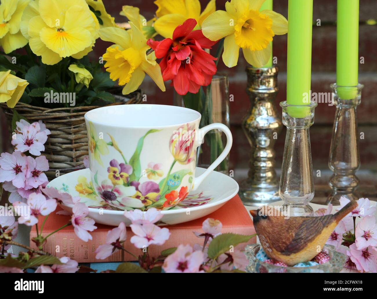 decoración de primavera con ramo de narcisos y tulipán, copa y pájaro decorativo Foto de stock