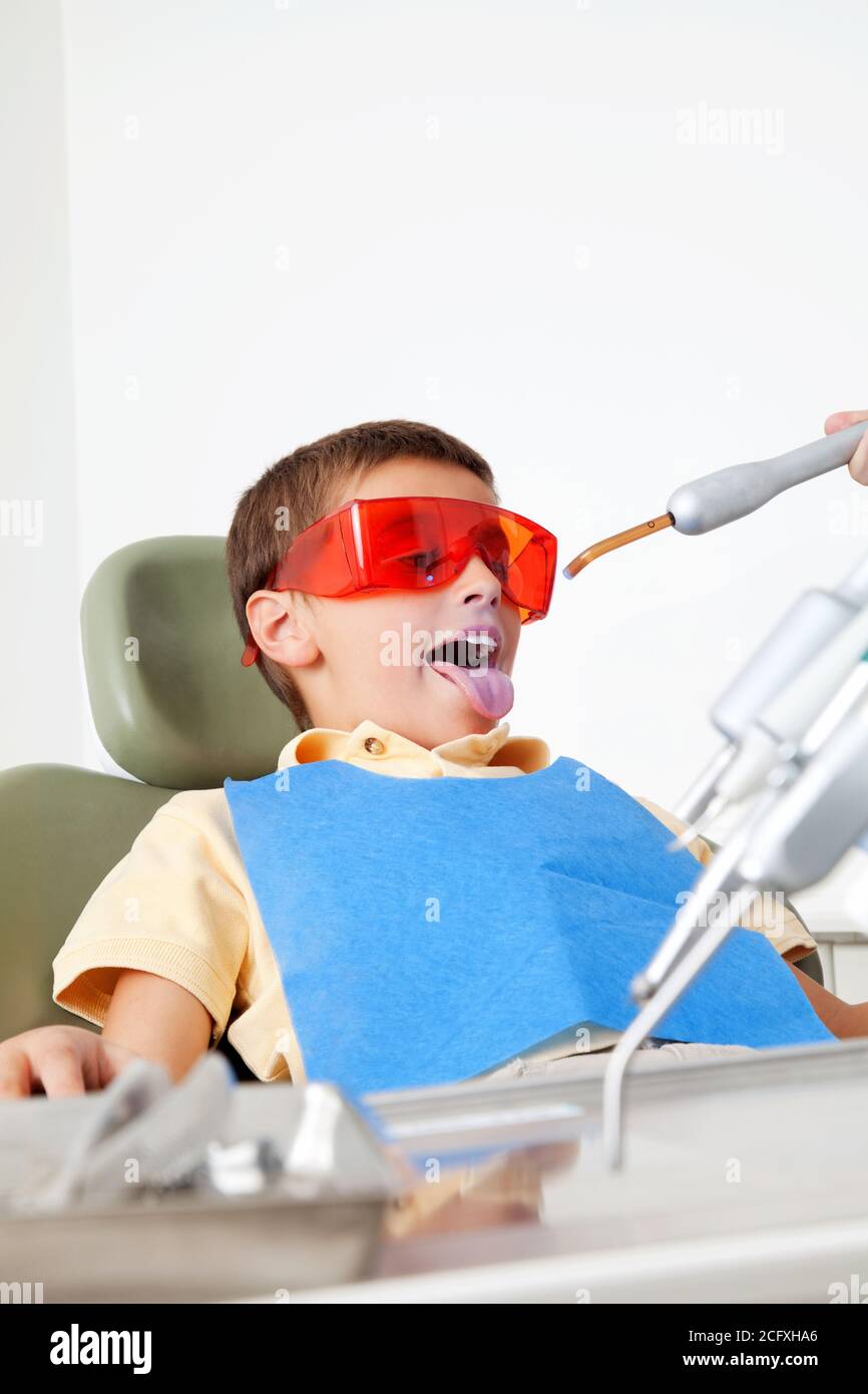 Un niño con gafas protectoras en el dentista le indica lengua Fotografía de  stock - Alamy