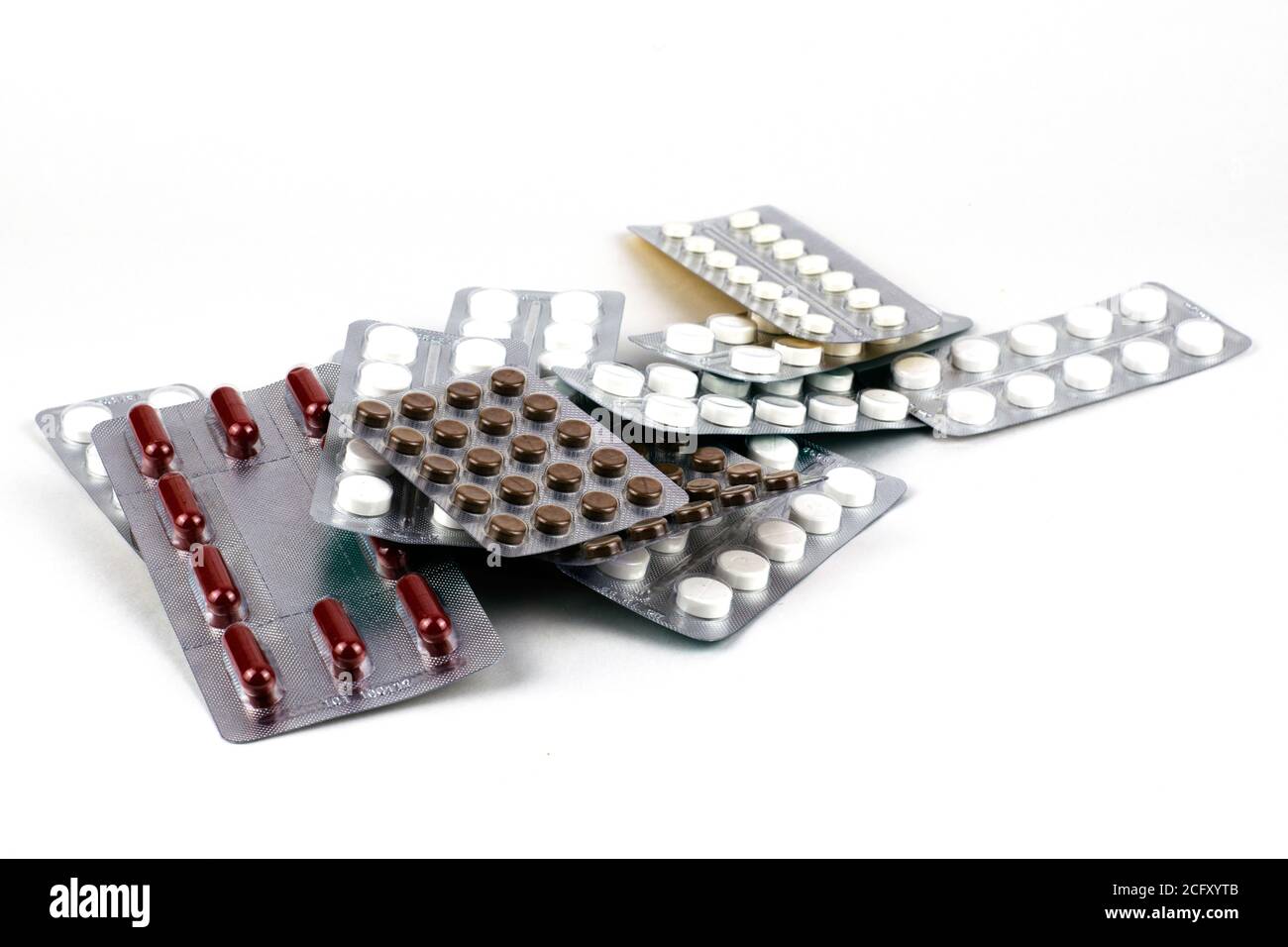 gran pila de diferentes píldoras en ampollas sobre un fondo blanco