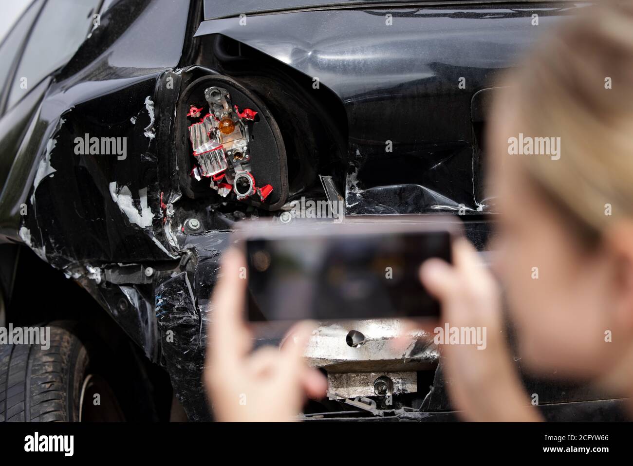 Mujer conductor tomando foto de coche dañado después del accidente para Reclamación del seguro en el teléfono móvil Foto de stock