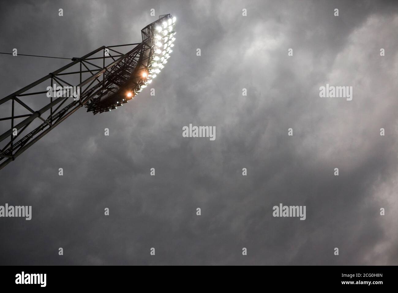 Mástil de focos contra el cielo dramático oscuro. Copiar espacio en el cielo. El ligero ruido debido a la alta iso se añade a la escena dramática. Foto de stock