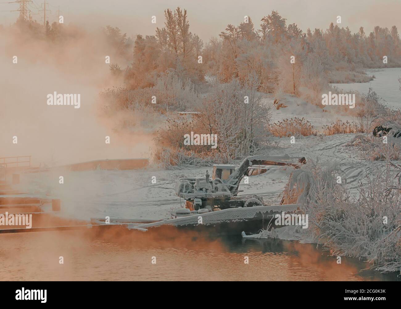 Viejo excavador entre árboles congelados. Misteriosa niebla sobre el río en el paisaje industrial Foto de stock