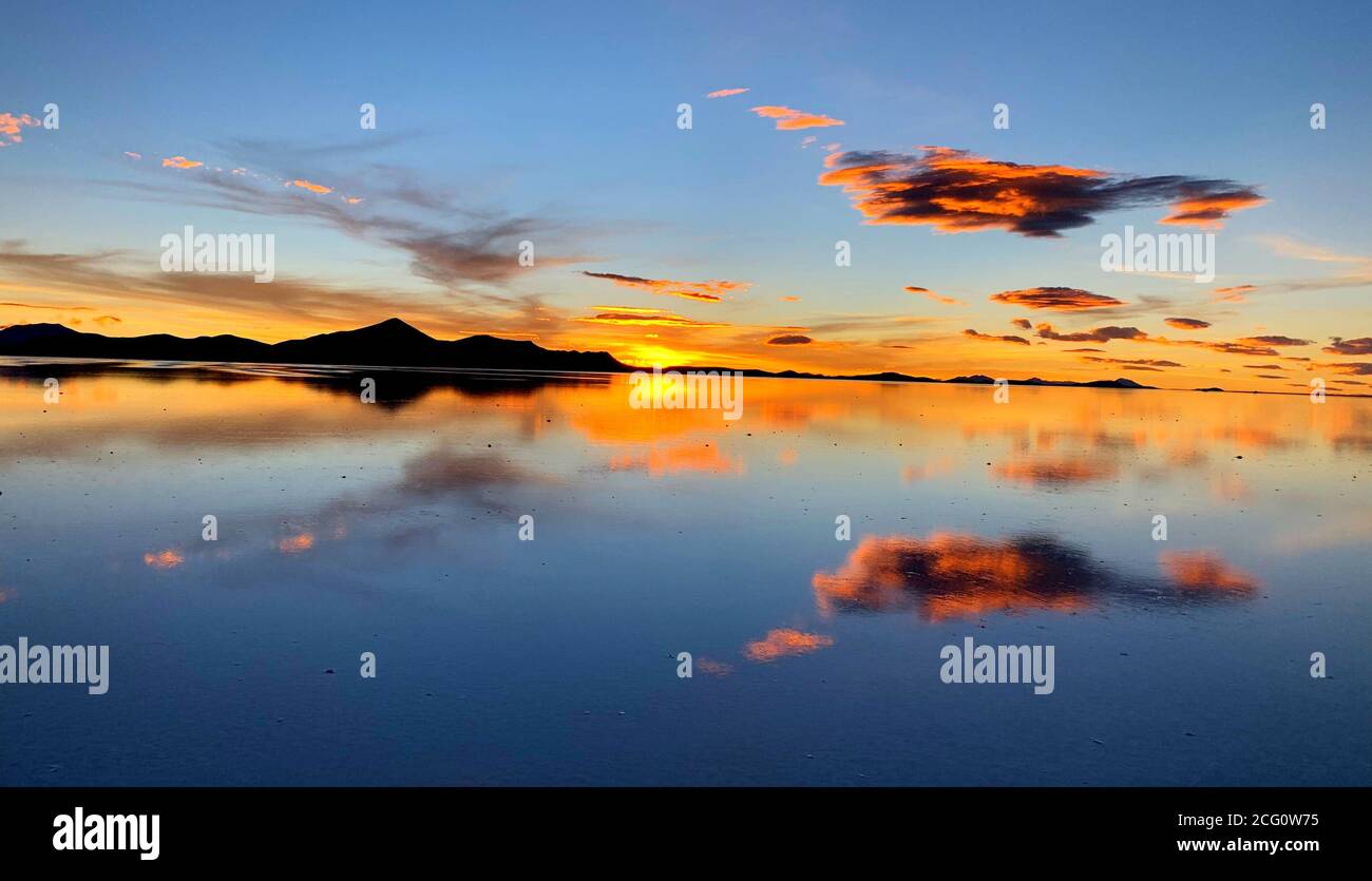Puesta de sol romántica sobre Saline Salar, Salar de Uyuni, Bolivia. Reflejo nublado en el lago salado. Crepúsculo por la noche. Nube esponjosa sobre agua salada. Foto de stock