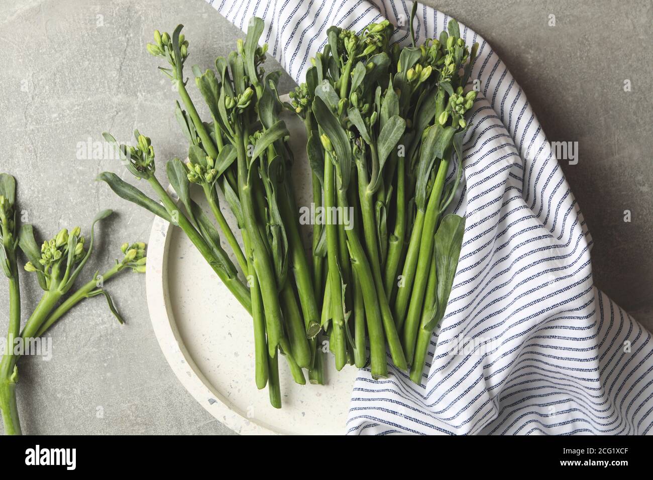 Bandeja con broccolini y servilleta sobre fondo gris Foto de stock