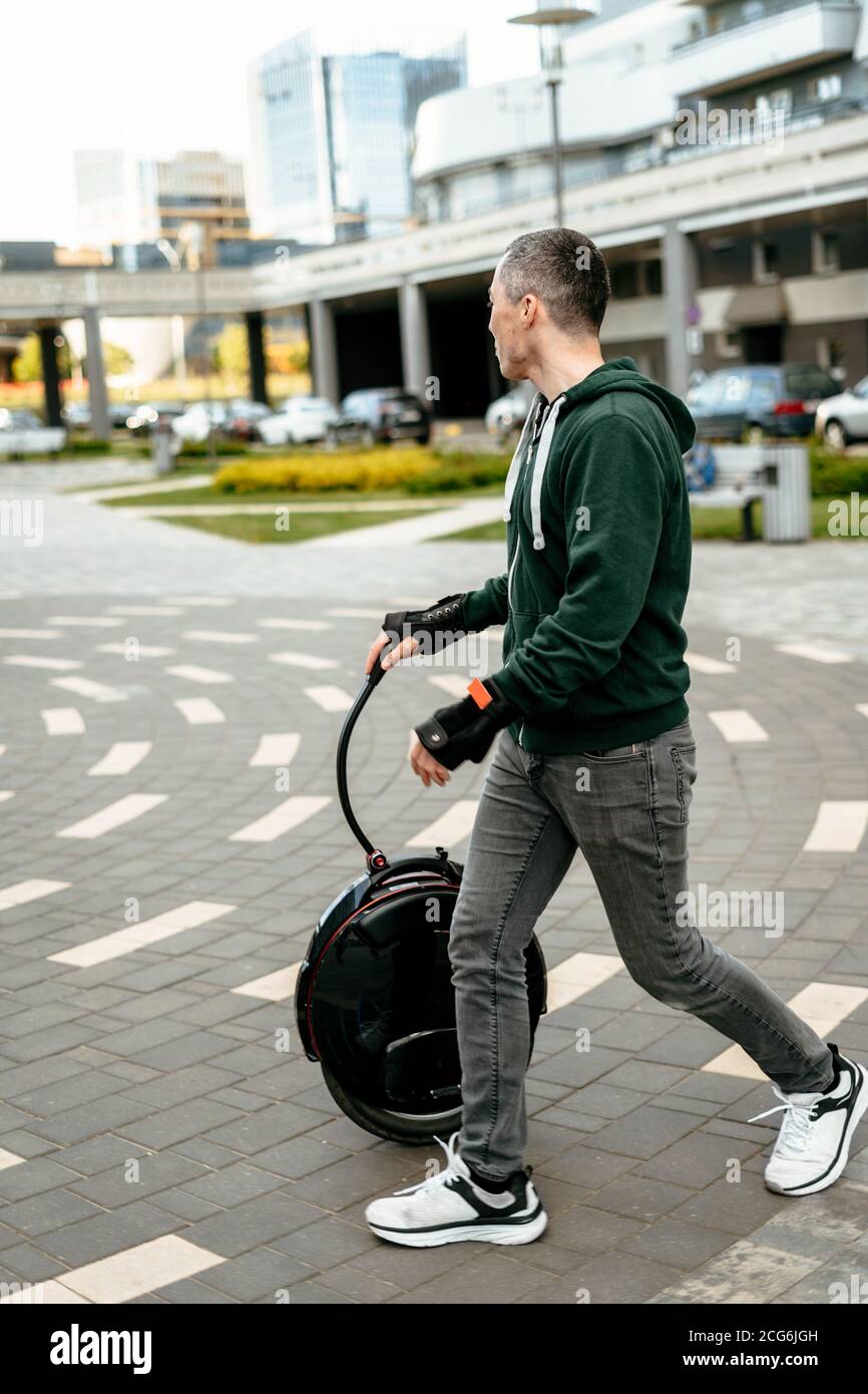 El hombre transporta un moniciclo en la calle, un moniciclo eléctrico de cerca. Foto de stock