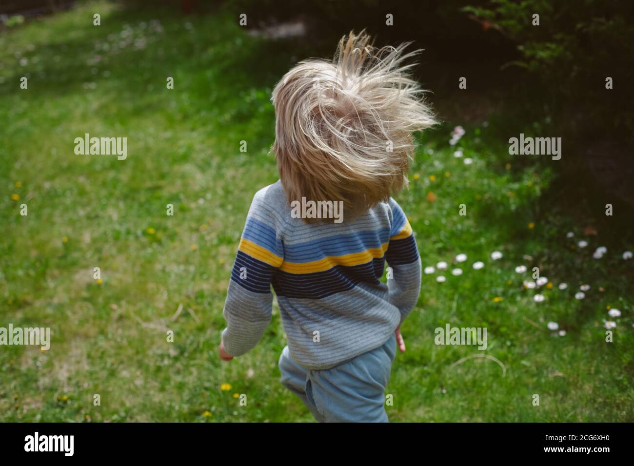 Vista trasera de un niño corriendo en un jardín Foto de stock