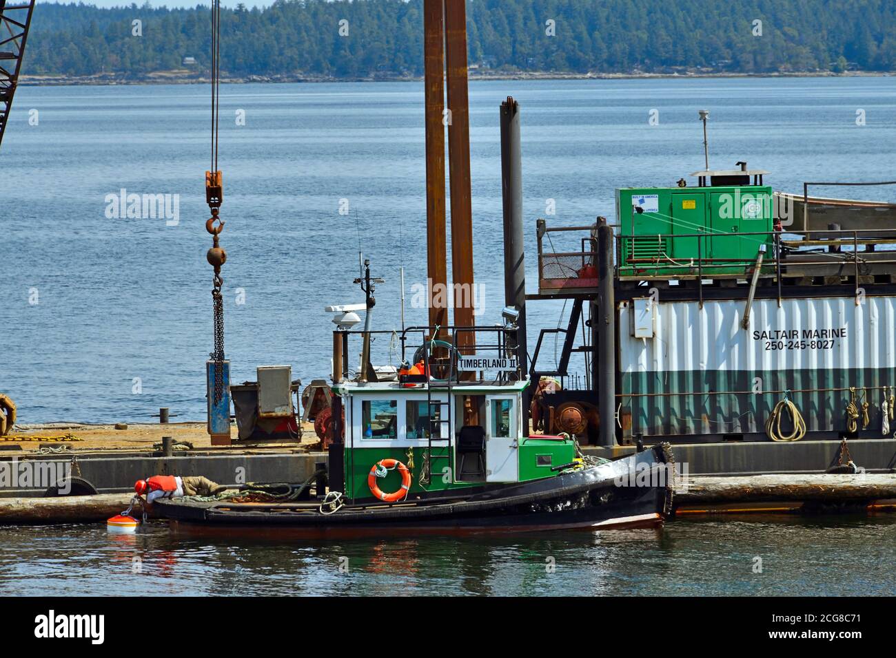 Un remolcador que sostiene una barcaza con una grúa móvil en el lugar para colocar un amarre bouy en el canal Stuart en la isla de Vancouver B.C., Canadá. Foto de stock