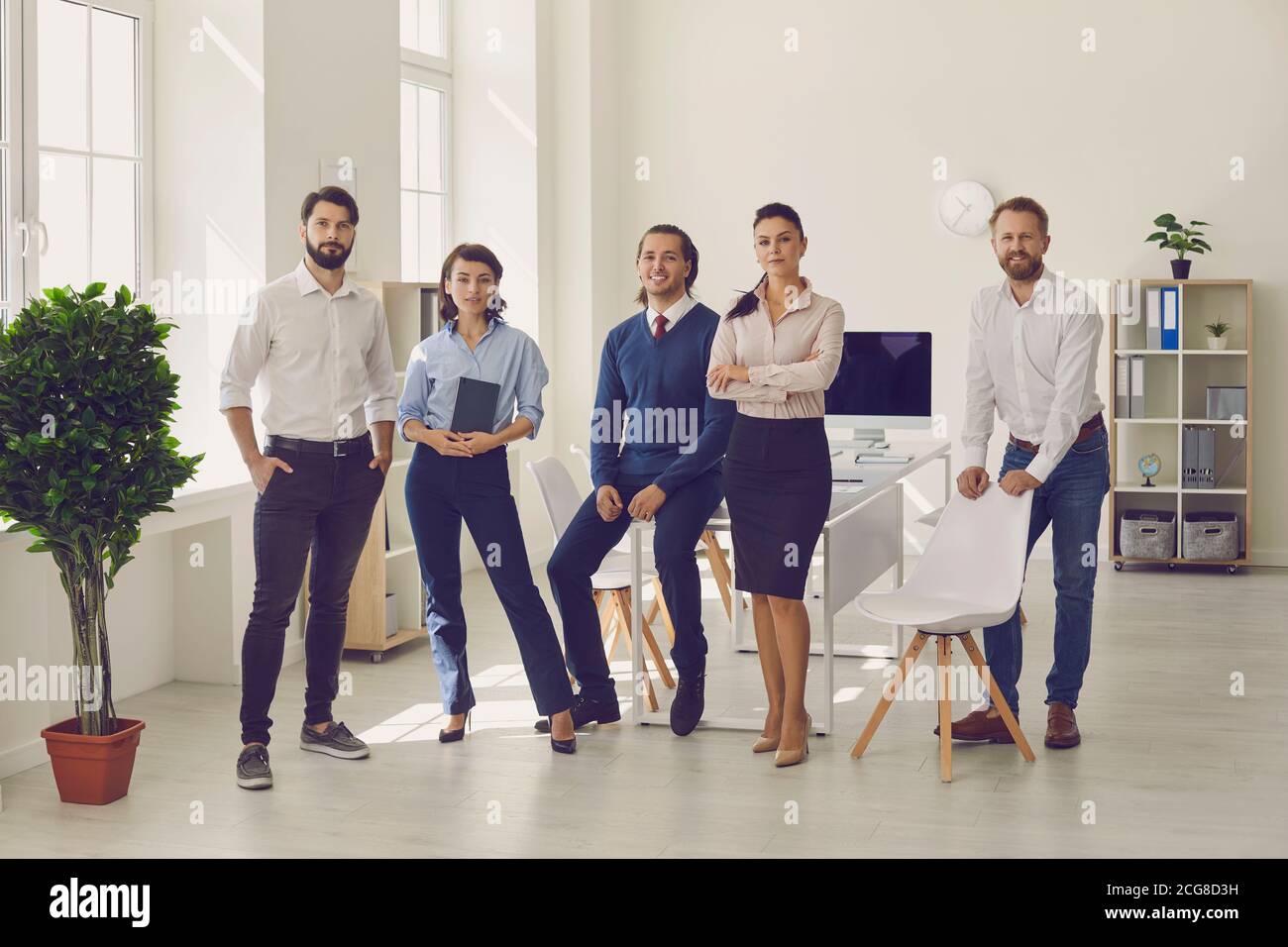 Grupo de jóvenes profesionales de pie en la oficina moderna listo para reunión corporativa Foto de stock