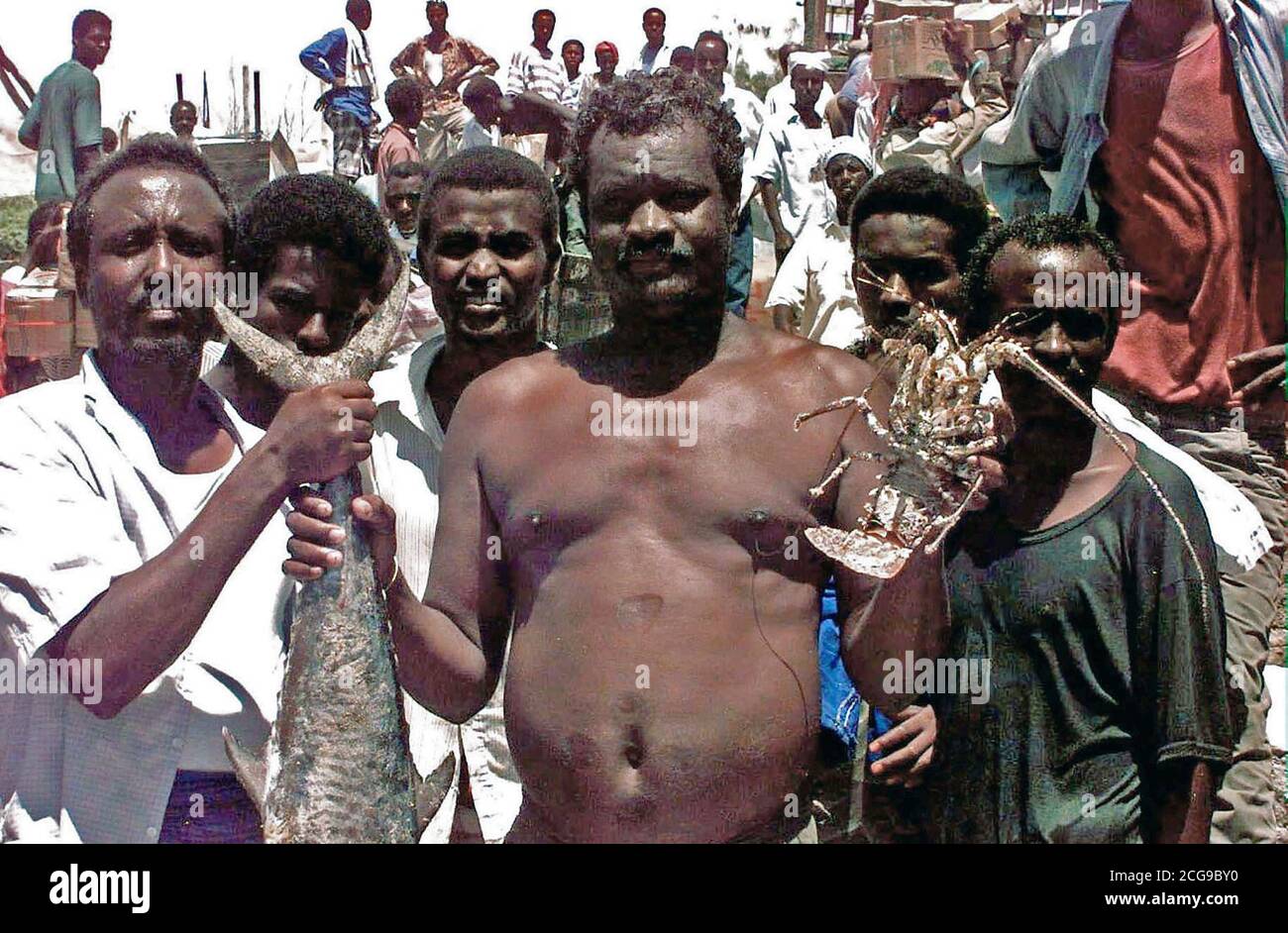 1993 - Dos hombres somalíes se enfrentan a la cámara y retener algunos de los mariscos disponibles en un mercado en la playa en Mogadishu. Otros cuatro hombres somalíes puesto justo detrás de los dos primeros y se enfrentan a la cámara. Foto de stock