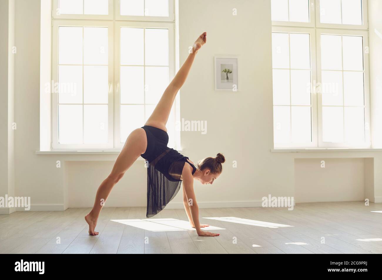 Buen aspecto delgado femenino gimnasta preparándose para hacer un puesto de mano en un estudio moderno Foto de stock