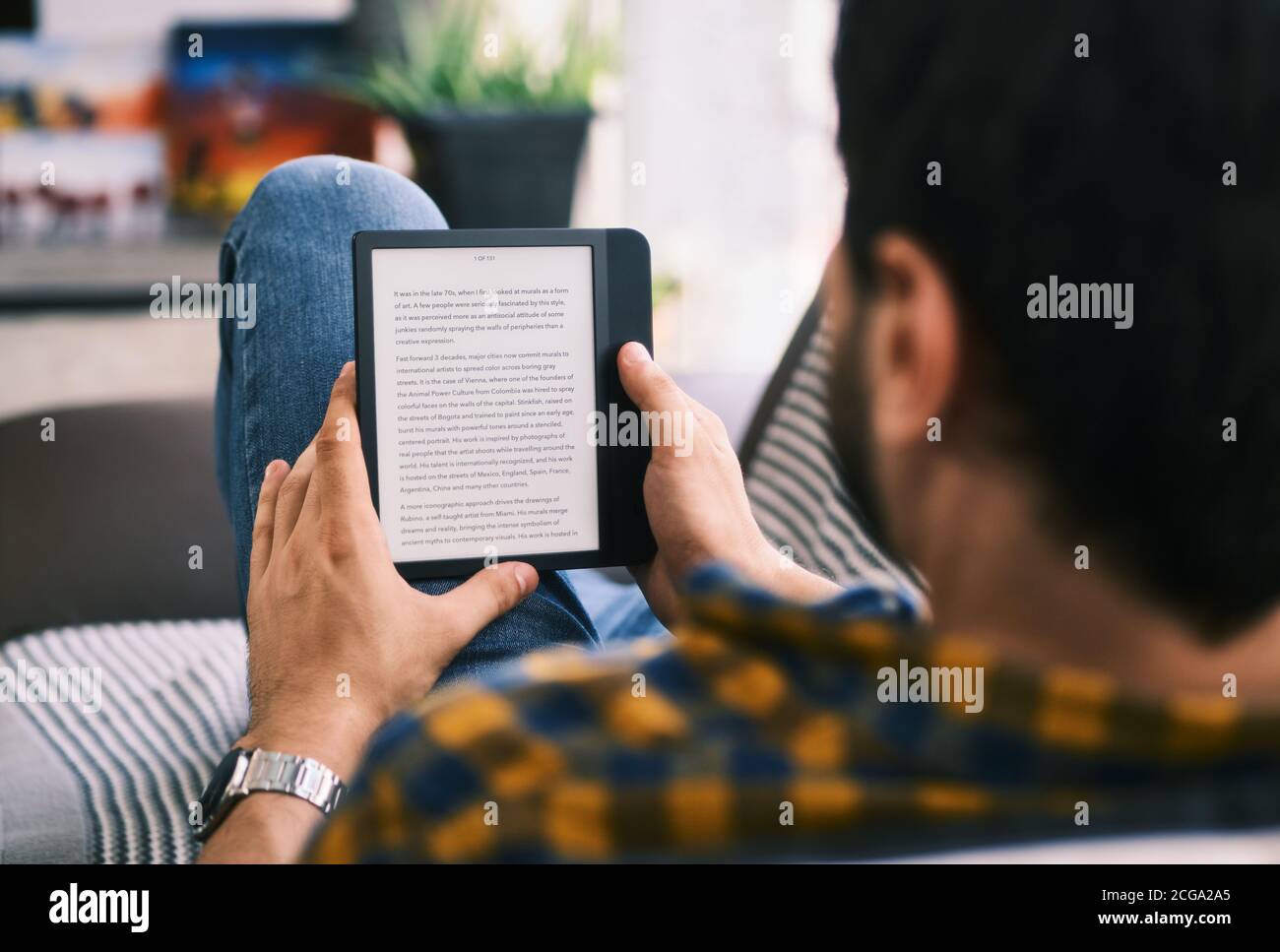 Hombre joven sosteniendo eReader y leyendo Ebook Foto de stock