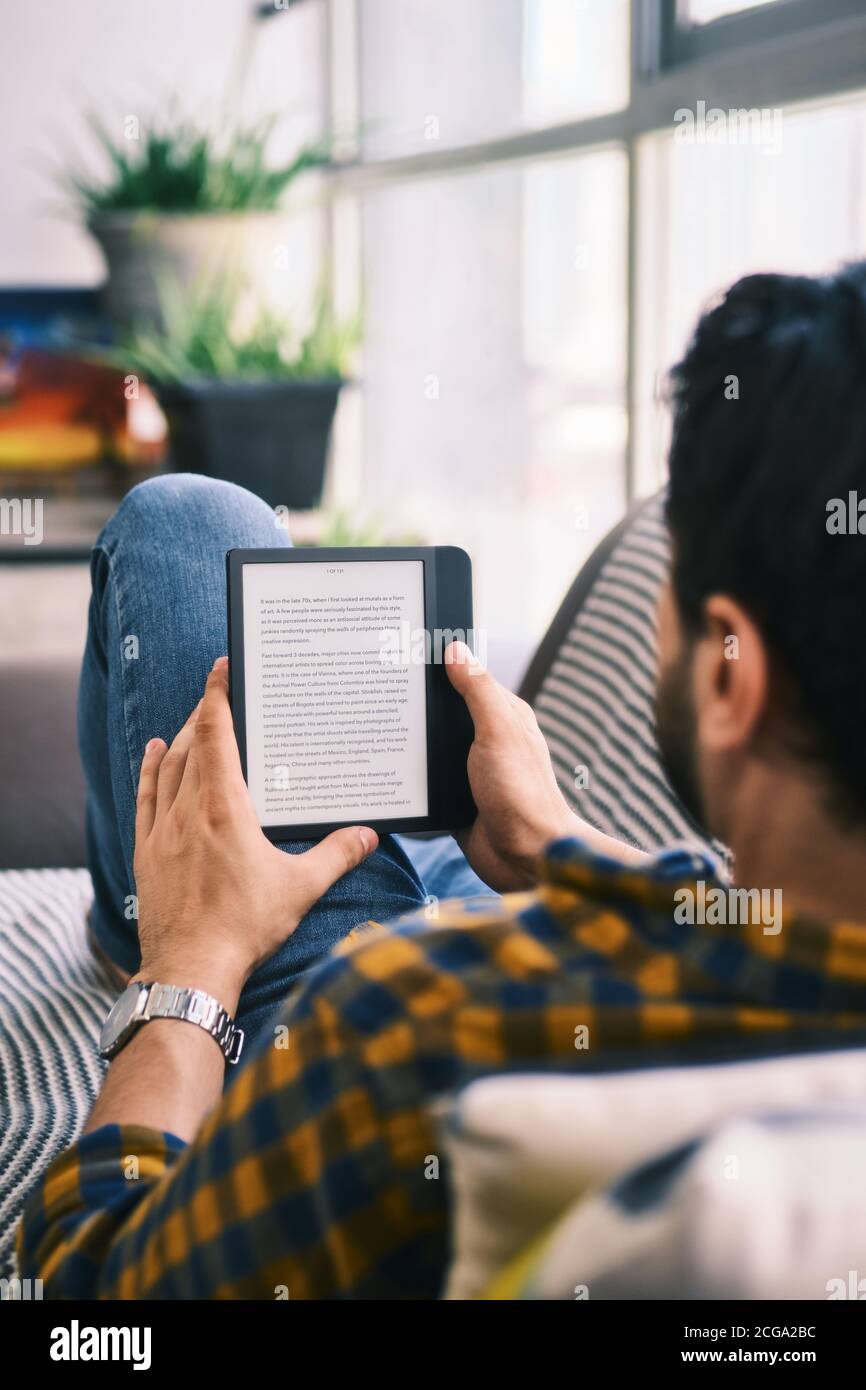 Hombre joven sosteniendo eReader y leyendo Ebook Foto de stock