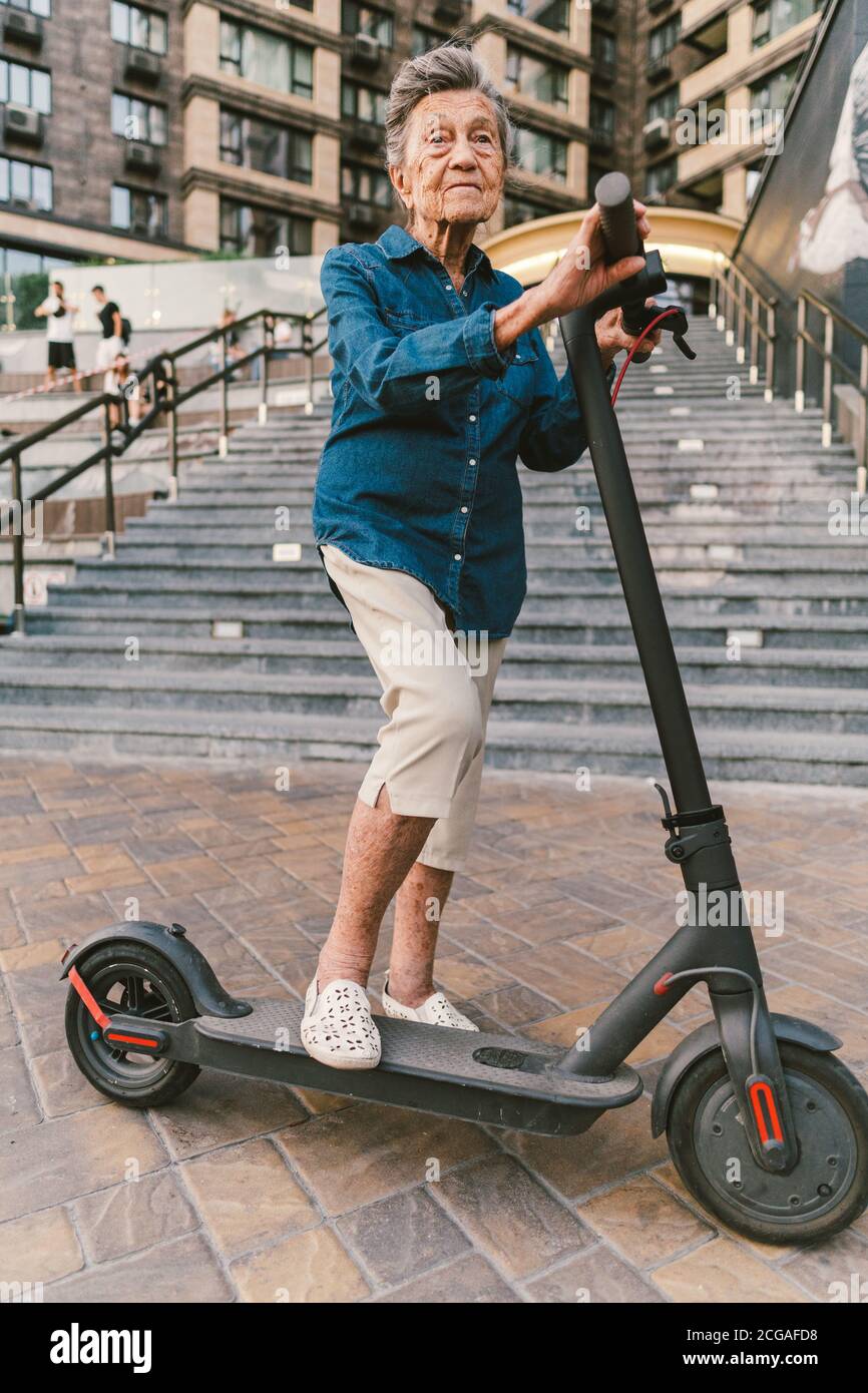 Alegre mujer anciana en una scooter. La abuela monta un scooter. Abuela  usando transporte personal urbano. Concepto de jubilación activa. Saludable  Fotografía de stock - Alamy