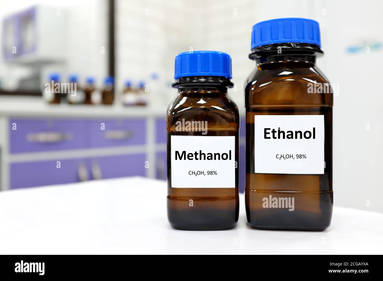 Foco selectivo de etanol y metanol en recipiente de botella de vidrio marrón. Fondo blanco de laboratorio con espacio de copia. Foto de stock