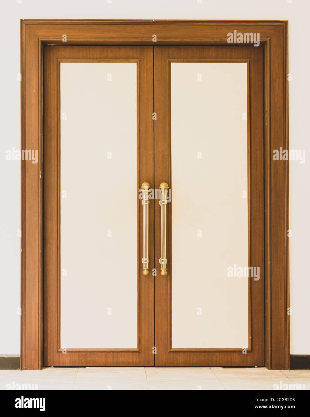 Puerta de oro vintage con asa en el lado frontal de la entrada interior de  la casa. Puertas de madera clara cerradas de primer plano en el interior. Accesorios  para puertas para