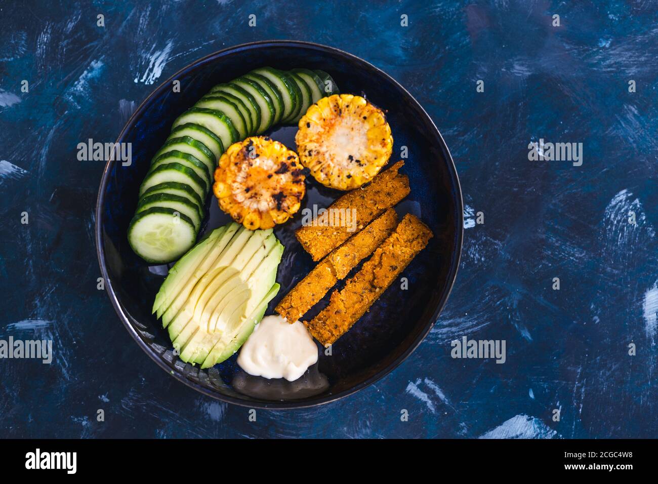 concepto de recetas saludables a base de plantas, cuenco nutritivo con  aguacate pepino polenta chips y maíz picante en la mazorca con mayo vegano  Fotografía de stock - Alamy