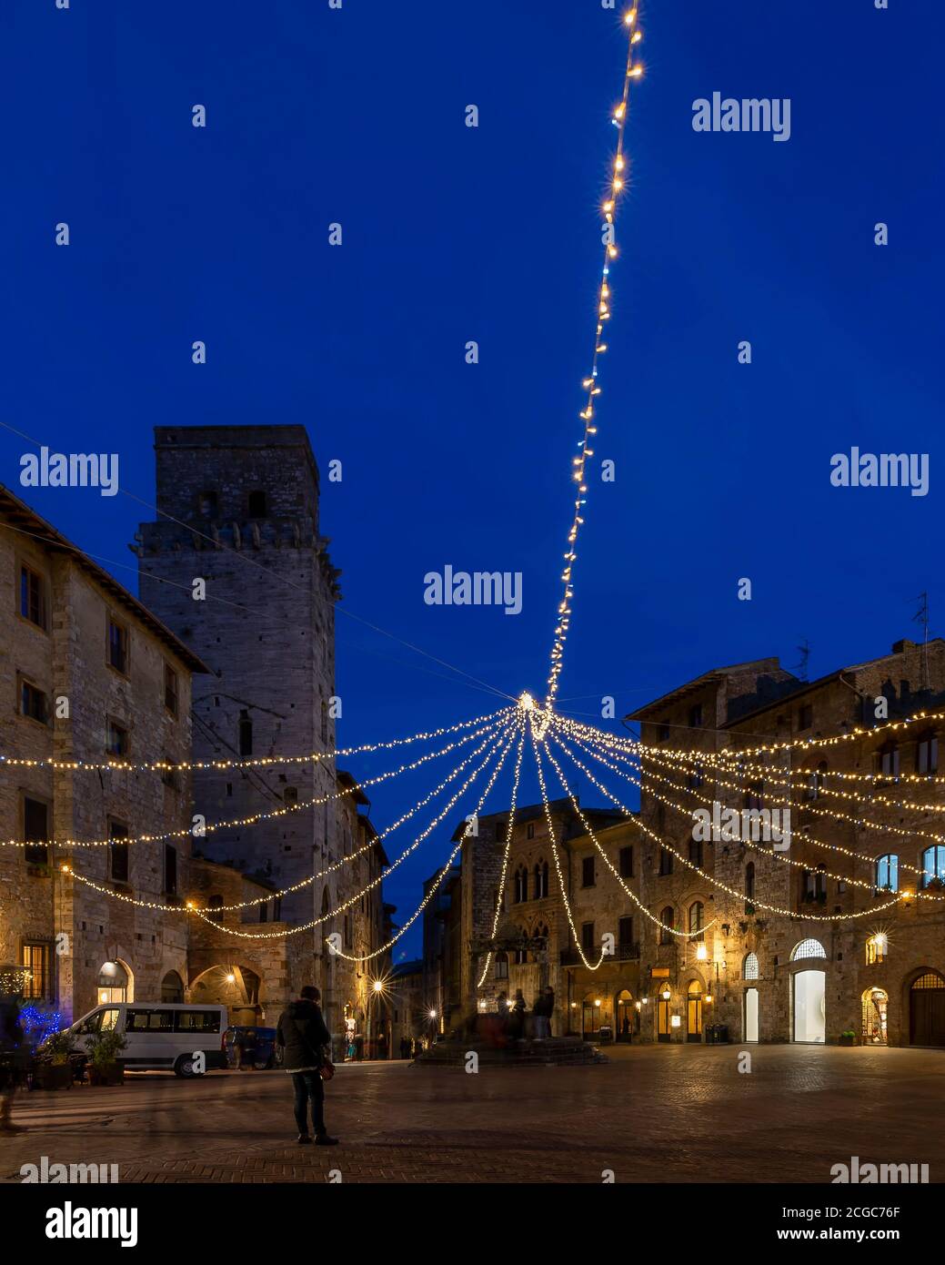 Vista vertical de la Piazza della Cisterna, centro histórico de San Gimignano, Siena, Italia, con las luces del atardecer en la hora azul Foto de stock