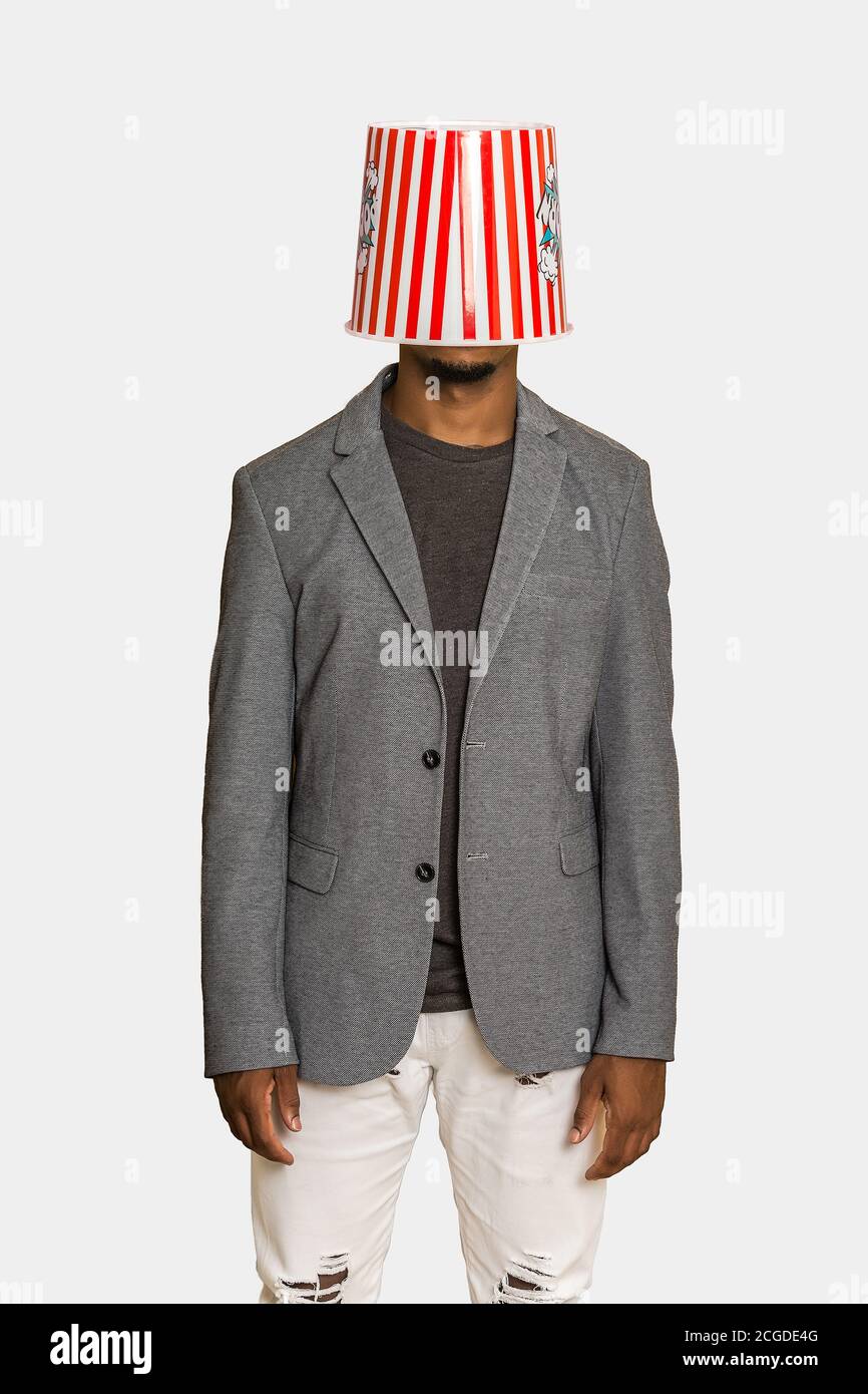 Hombre irreconocible en conjunto elegante sport usando cubo de palomitas de  maíz a rayas en la cabeza contra fondo gris Fotografía de stock - Alamy