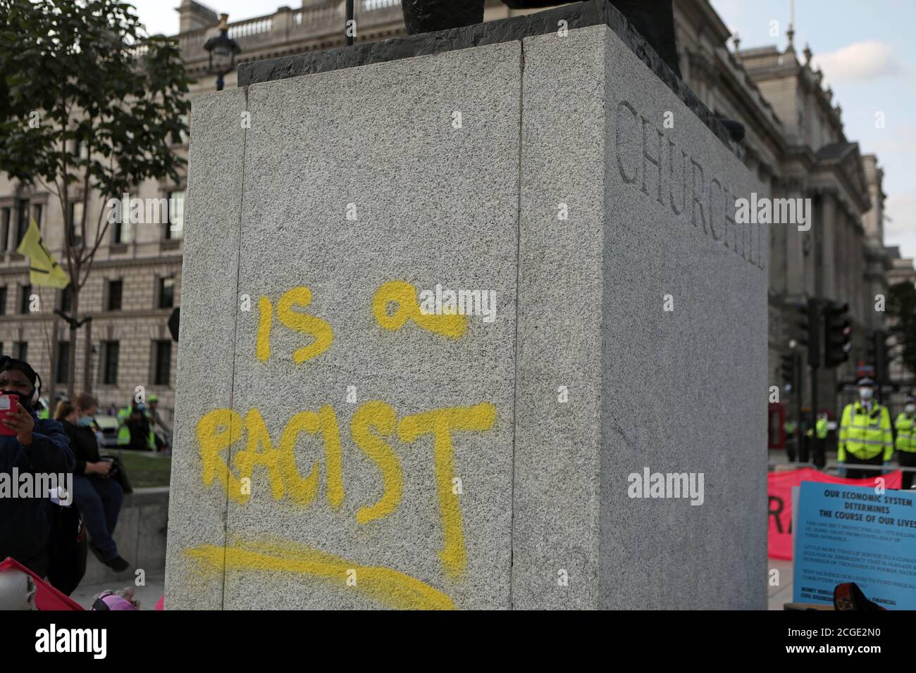 El zócalo de la estatua de Winston Churchill, después de que fue destrozada con las palabras "ES UN RACISTA" rociado en pintura amarilla, en la Plaza del Parlamento, Londres, en el último día de manifestaciones. Foto de stock