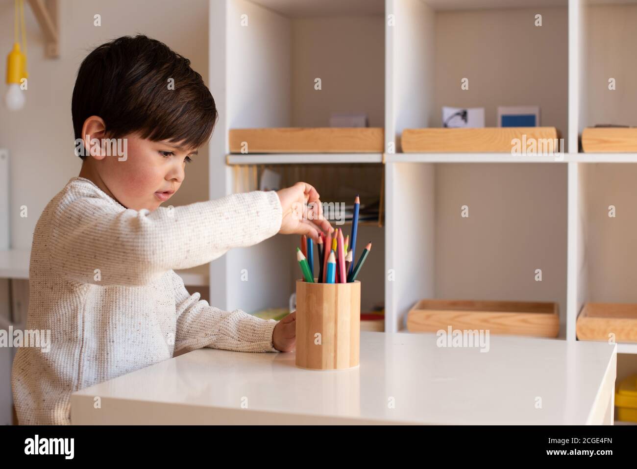 Pequeño niño de preescolar dibujo con lápices de colores. Homeschooling. Comunidad de aprendizaje. Escuela Montessori. Foto de stock