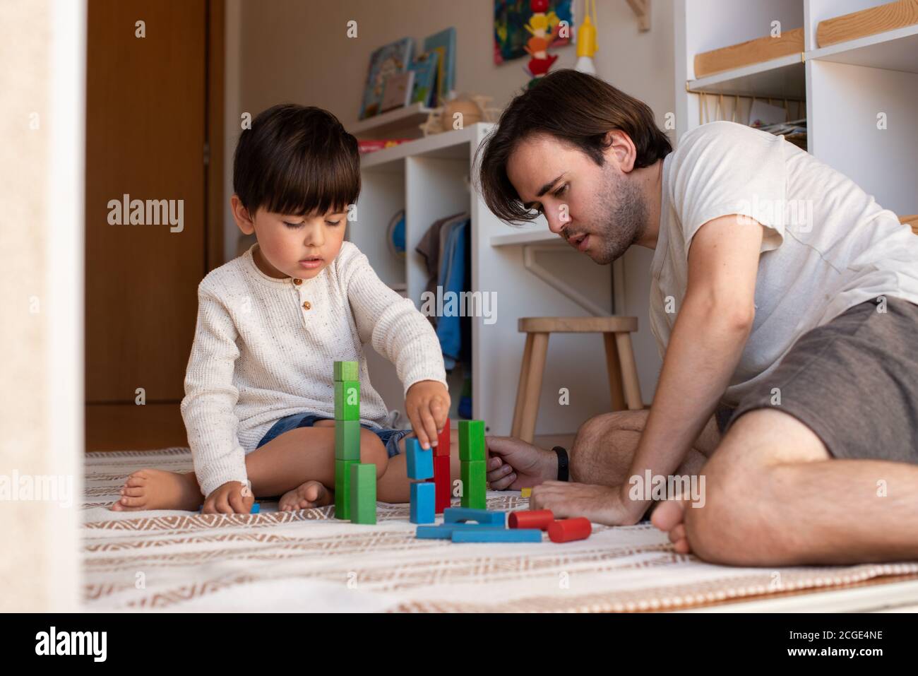 Niño pequeño y su padre jugando en casa con bloques de madera. Homeschooling. Quédate en casa. Tiempo en familia Foto de stock