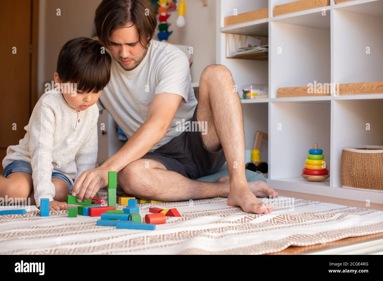 Niño pequeño y su padre jugando en casa con bloques de madera. Homeschooling. Quédate en casa. Tiempo en familia Foto de stock