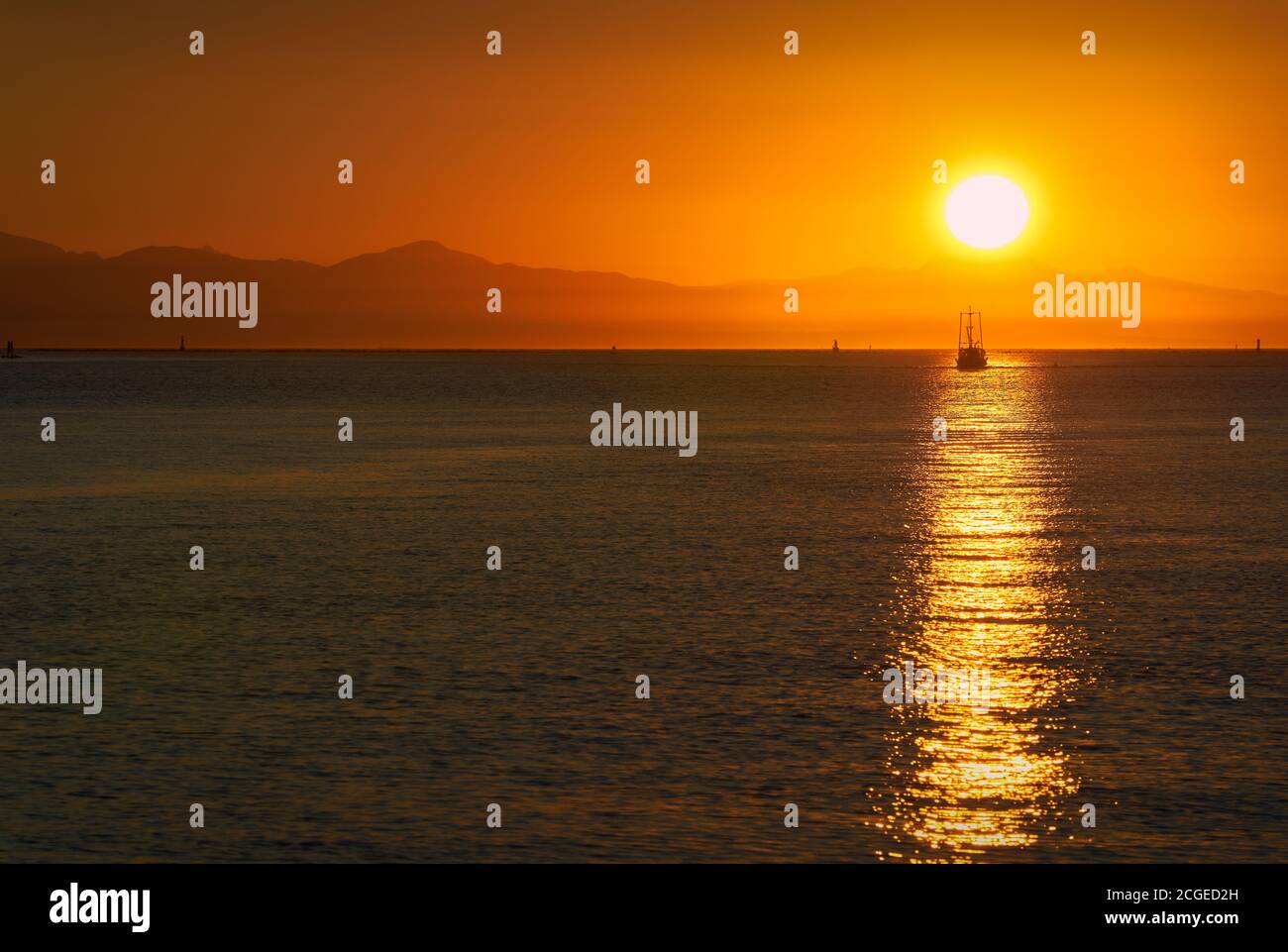 Barco de pescado Sunset del Estrecho de Georgia. Un barco de pesca que regresa del Estrecho de Georgia y del Mar de Salish al atardecer. Isla de Vancouver al fondo. Foto de stock